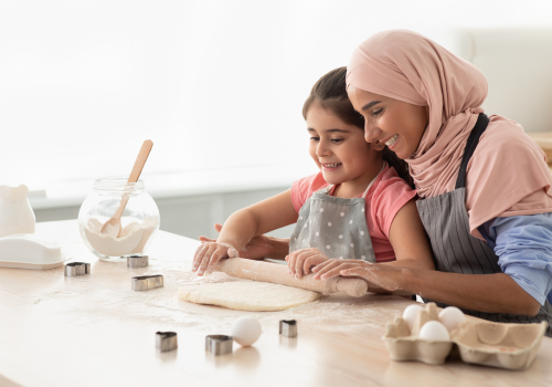 Muslim woman and child rolling out pastry